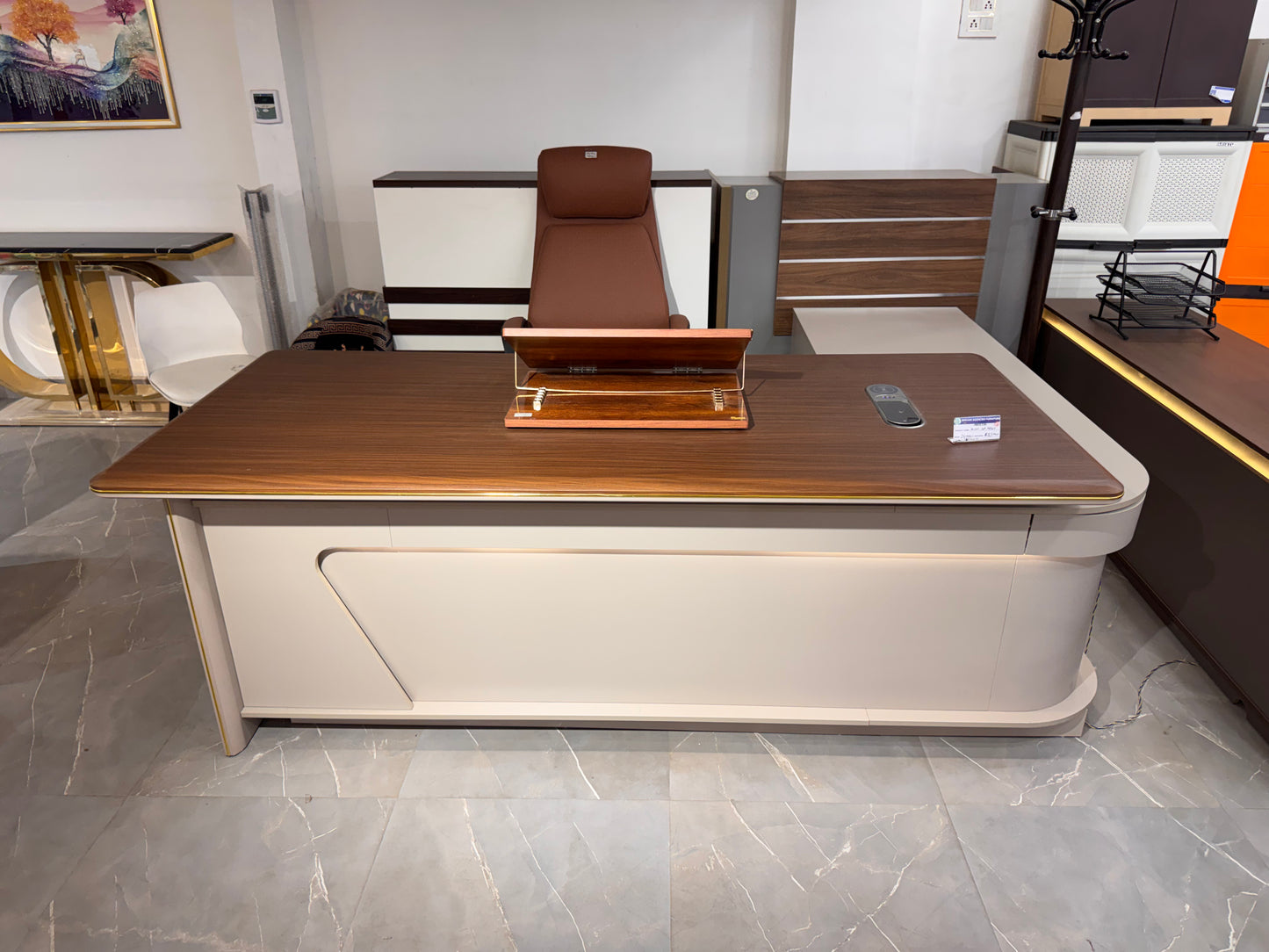 Modern office desk with wooden top and beige base in a showroom setting.