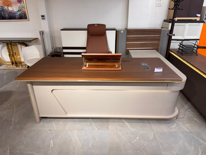 Modern office desk with wooden top and beige base in a showroom setting.